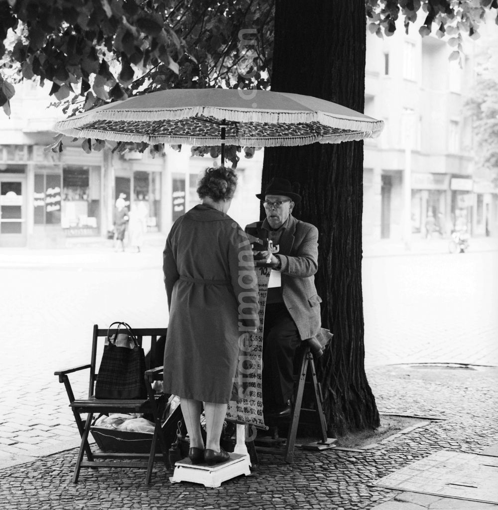 GDR photo archive: Berlin - With hat and suit dressed elderly gentleman in weighing of road passersby on the Schoenhauser Allee in Berlin, the former capital of the GDR, German Democratic Republic. For a Woman can be or a passing Obolus 1