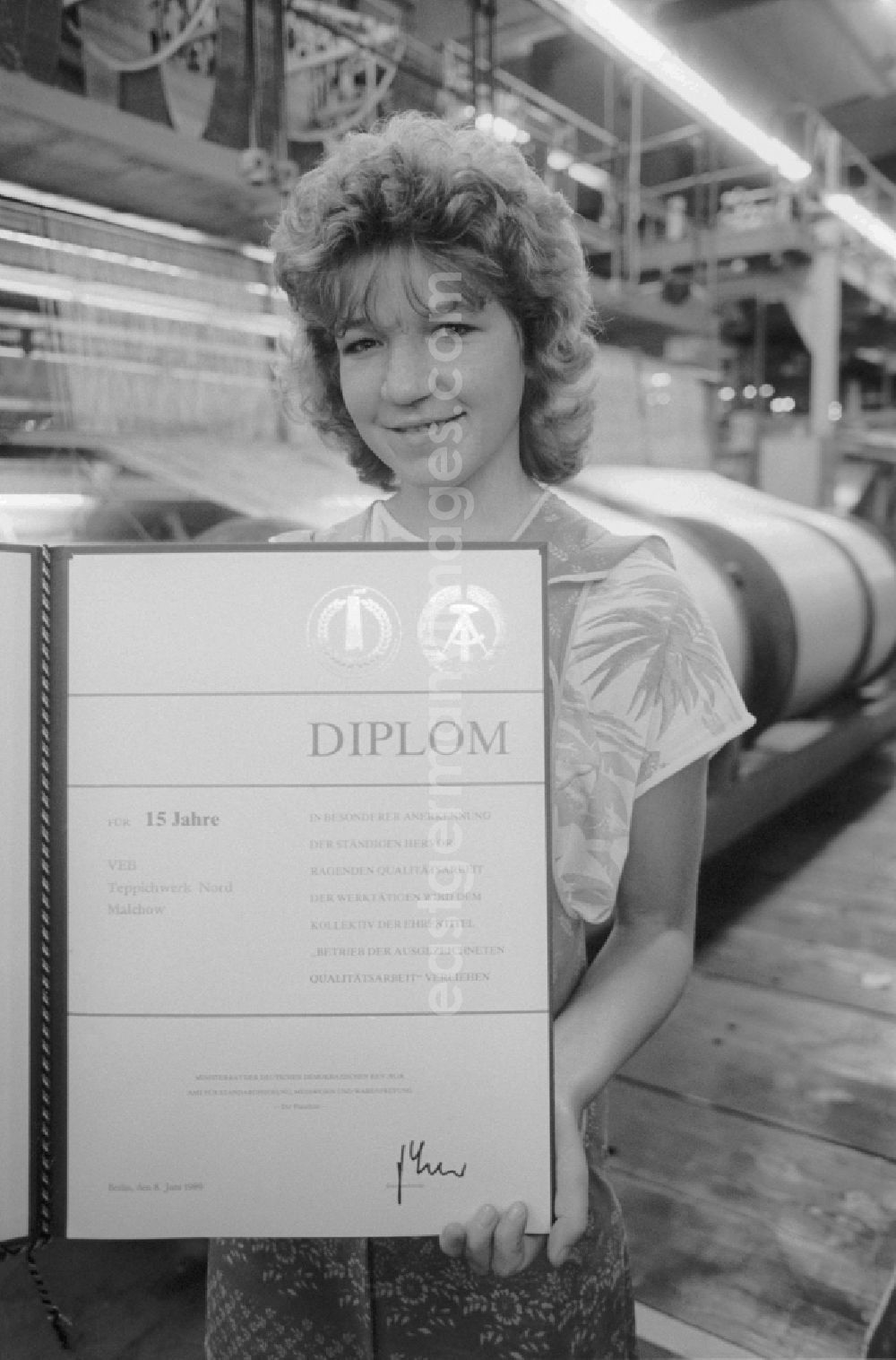 GDR photo archive: Malchow - As the first operation of the textile industry of the GDR received the Carpet Factory North Malchow, district Waren, the Honorary Diploma 15 Years of operation of the excellent quality of work in Malchow in Mecklenburg-Western Pomerania in the field of the former GDR, German Democratic Republic. It maintains a staff in his hand and shows it with pride
