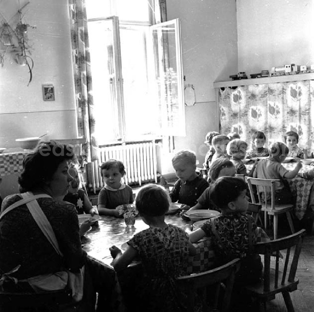 GDR image archive: Brandenburg - Kinder sitzen zusammen am Tisch beim Mittagessen im Kindergarten, Erzieherin sitzt daneben.