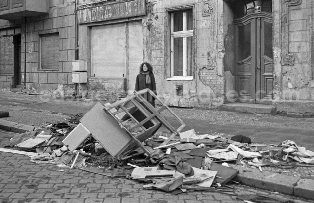 GDR photo archive: Berlin - Fashion and clothing of street passers-by in front of street garbage piles on street Schreinerstrasse in the district Friedrichshain in Berlin Eastberlin on the territory of the former GDR, German Democratic Republic