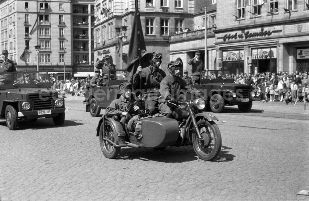 GDR photo archive: Magdeburg - Uniformed and motorized units of the combat groups of the GDR at the parade on May 1 in Magdeburg. Here when passing with a military salute. In the foreground members of the Battle Group on a motorcycle with a sidecar and troop flag