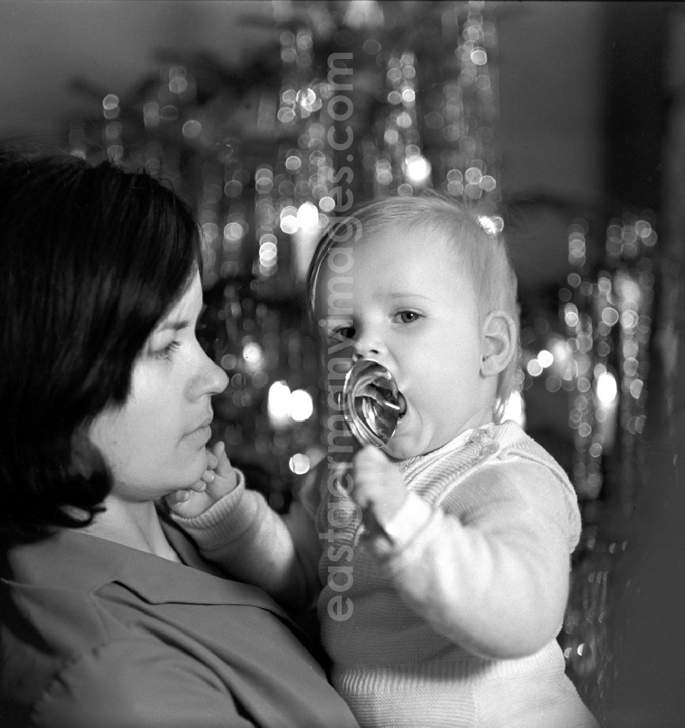 GDR picture archive: Berlin - Friedrichshain - Mother with baby in her arms in front of a Christmas tree in Berlin - Friedrichshain