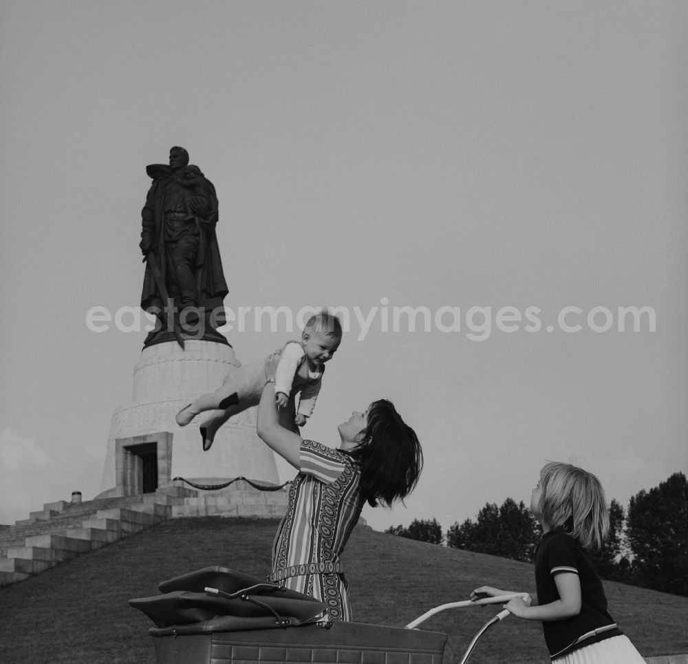 GDR photo archive: Berlin - Treptow - Mother walking with baby carriage in the memorial walk Soviet War Memorial in Treptower Park. In the background the stature and Child with broken swastika. The plant was built in honor of the Soviet soldiers killed in World War 2