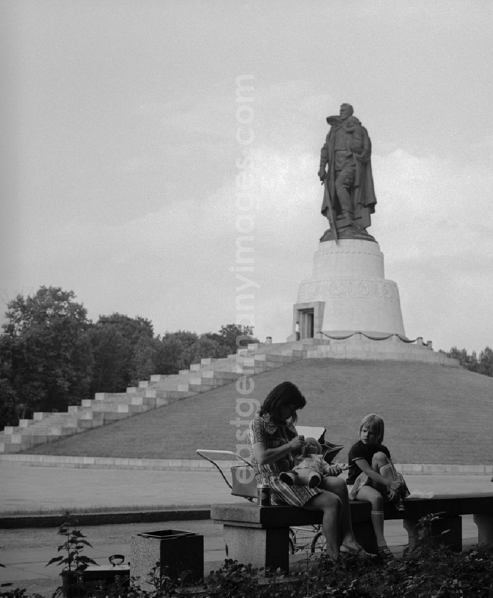 GDR picture archive: Berlin - Treptow - Mother walking with baby carriage in the memorial walk Soviet War Memorial in Treptower Park. In the background the stature and Child with broken swastika. The plant was built in honor of the Soviet soldiers killed in World War 2