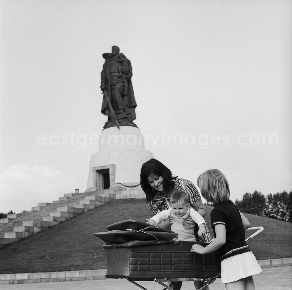 GDR image archive: Berlin - Treptow - Mother walking with baby carriage in the memorial walk Soviet War Memorial in Treptower Park. In the background the stature and Child with broken swastika. The plant was built in honor of the Soviet soldiers killed in World War 2