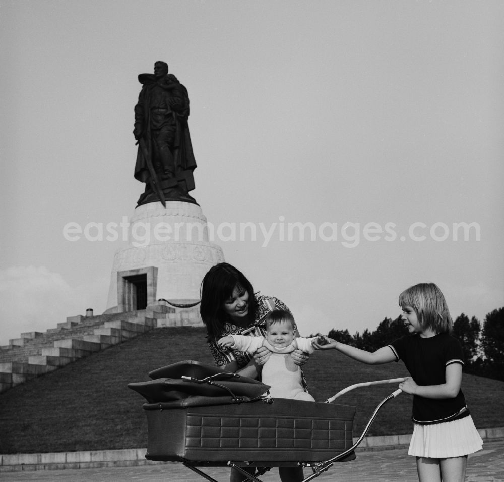 GDR photo archive: Berlin - Treptow - Mother walking with baby carriage in the memorial walk Soviet War Memorial in Treptower Park. In the background the stature and Child with broken swastika. The plant was built in honor of the Soviet soldiers killed in World War 2