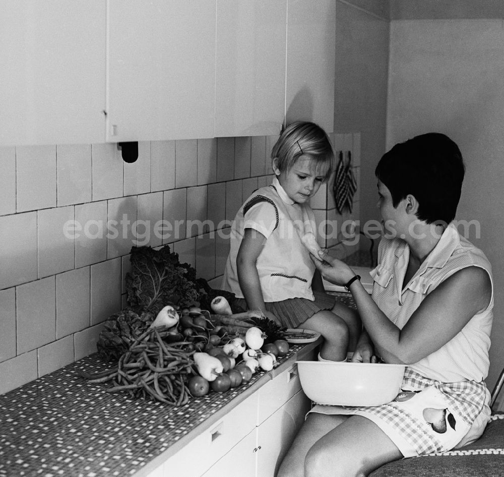 Berlin - Friedrichshain: A mother sits with her child in the kitchen and dressing vegetables in Berlin - Friedrichshain