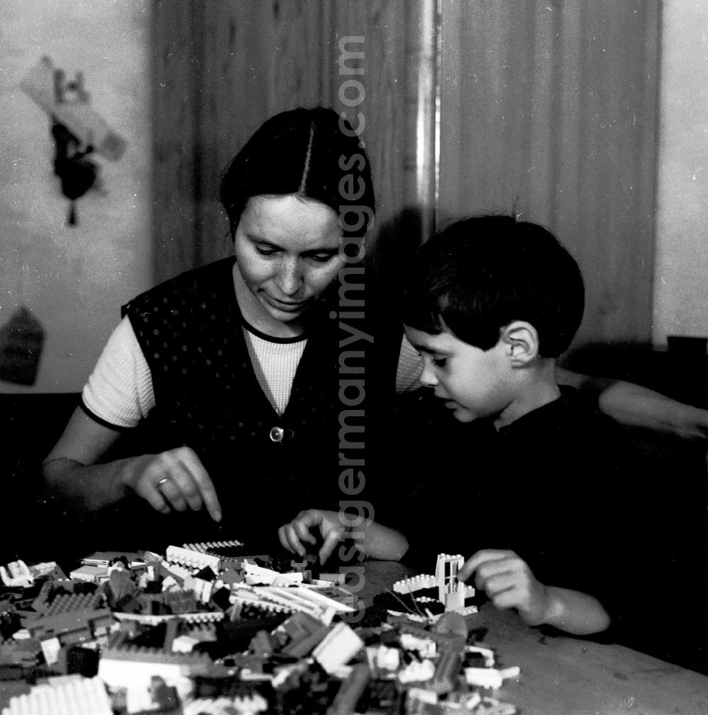 GDR photo archive: Berlin - A mother plays with her child with plastic PEBE to stones in Berlin, the former capital of the GDR, German democratic republic. This plastic boxes of building blocks were the LEGO of the GDR