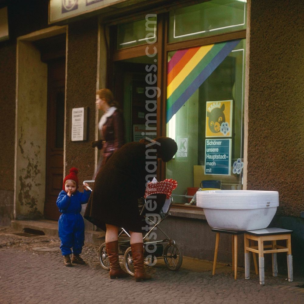 GDR picture archive: Berlin - Mother by baby carriage and a toddler before a HO business for household articles in Berlin, the former capital of the GDR, German democratic republic