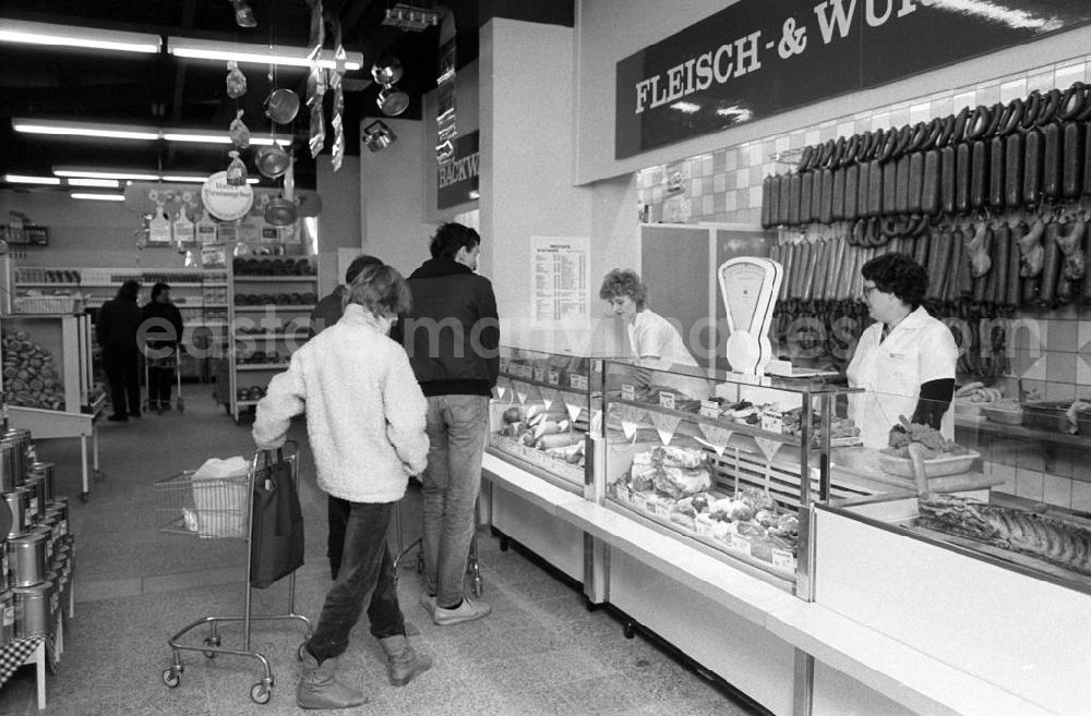 GDR photo archive: Berlin - Anwohner in der neuen Kaufhalle in Berlin-Hellersdorf an der Fleischtheke / Wursttheke. Ein Frau schiebt einen Einkaufswagen.