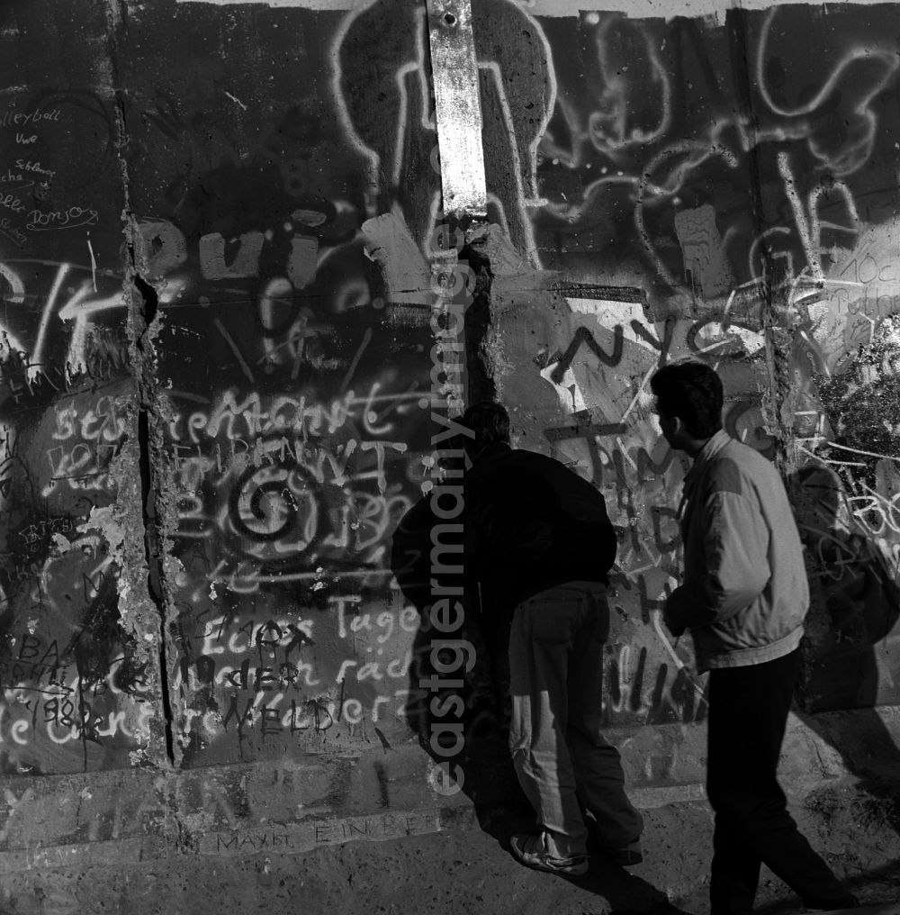 Berlin: Curious tourists and Berlin look through a hole in the Berlin wall on the other side of Berlin