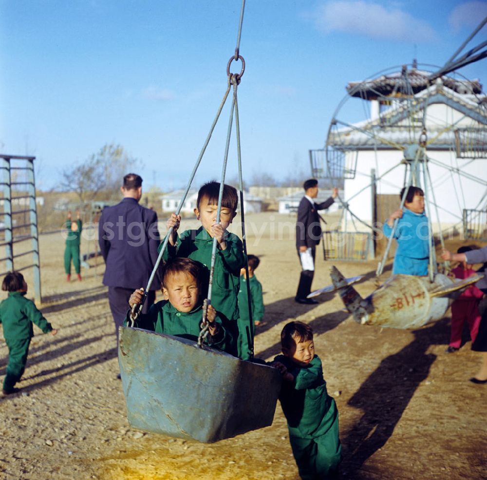 GDR photo archive: Hamhung - Kinder in Einheitsanzügen spielen auf einem Spielplatz in einem LPG-Kindergarten nahe der Hafenstadt Hamhung in der Koreanischen Demokratischen Volksrepublik KDVR.