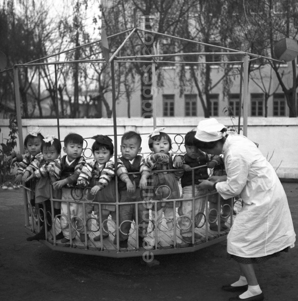 GDR photo archive: Pjöngjang - Kinder stehen in einem Karussell auf dem Spielplatz in einem Kindergarten in Pjöngjang, der Hauptstadt der Koreanischen Demokratischen Volksrepublik KDVR - Nordkorea / Democratic People's Republic of Korea DPRK - North Korea.