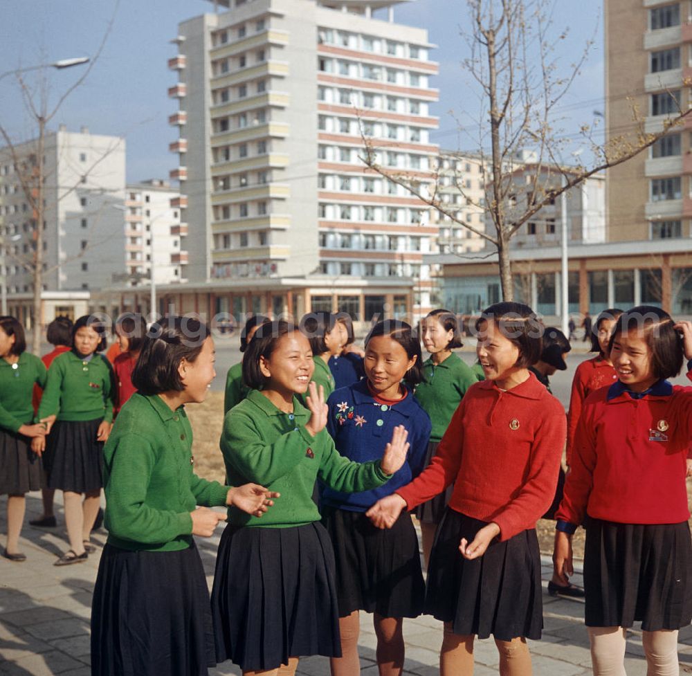 GDR picture archive: Pjöngjang - Schulmädchen auf einer Straße in Pjöngjang, der Hauptstadt der Koreanischen Demokratischen Volksrepublik (KDVR). Im Hintergrund Plattenbauten im sozialistischen Stil. Die nordkoreanische Hauptstadt war nach der Zerstörung im Koreakrieg vor allem mit Unterstützung der Sowjetunion in den 50er und 6