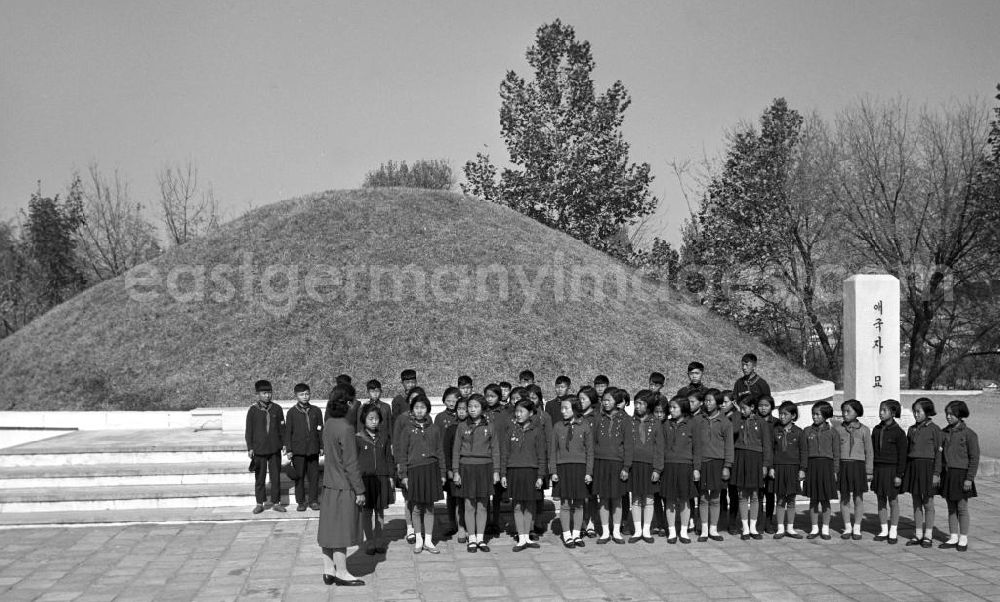 GDR picture archive: Sinchon - Nordkoreanische Pioniere stehen vor einem Massengrab-Hügel im Sinchon-Museum über US-Amerikanische Kriegsverbrechen in der der Koreanischen Demokratischen Volksrepublik KDVR - Nordkorea / Democratic People's Republic of Korea DPRK - North Korea.