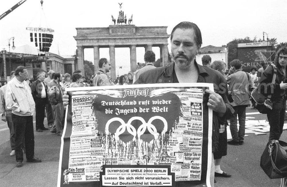 GDR picture archive: Berlin - Olympiafest am Brandenburger Tor, Mann hält Plakat mit der Aufschrift Aufruf Deutschland ruft wieder die Jugend der Welt... in die Kamera. Foto: Lange Umschlagsnr.: 1993-245