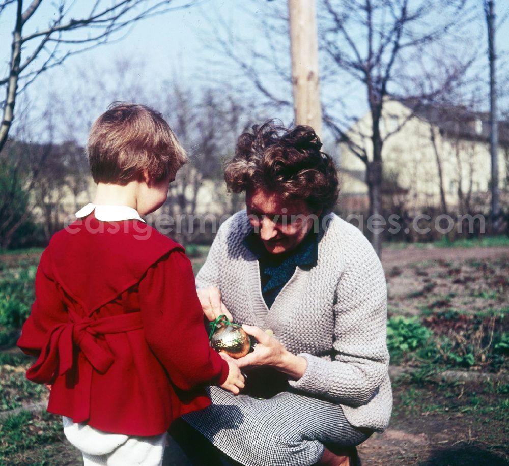 GDR image archive: Zschopau - A small child in a red dress with the Easter egg look in the garden in Zschopau in the federal state Saxony in the area of the former GDR, German democratic republic