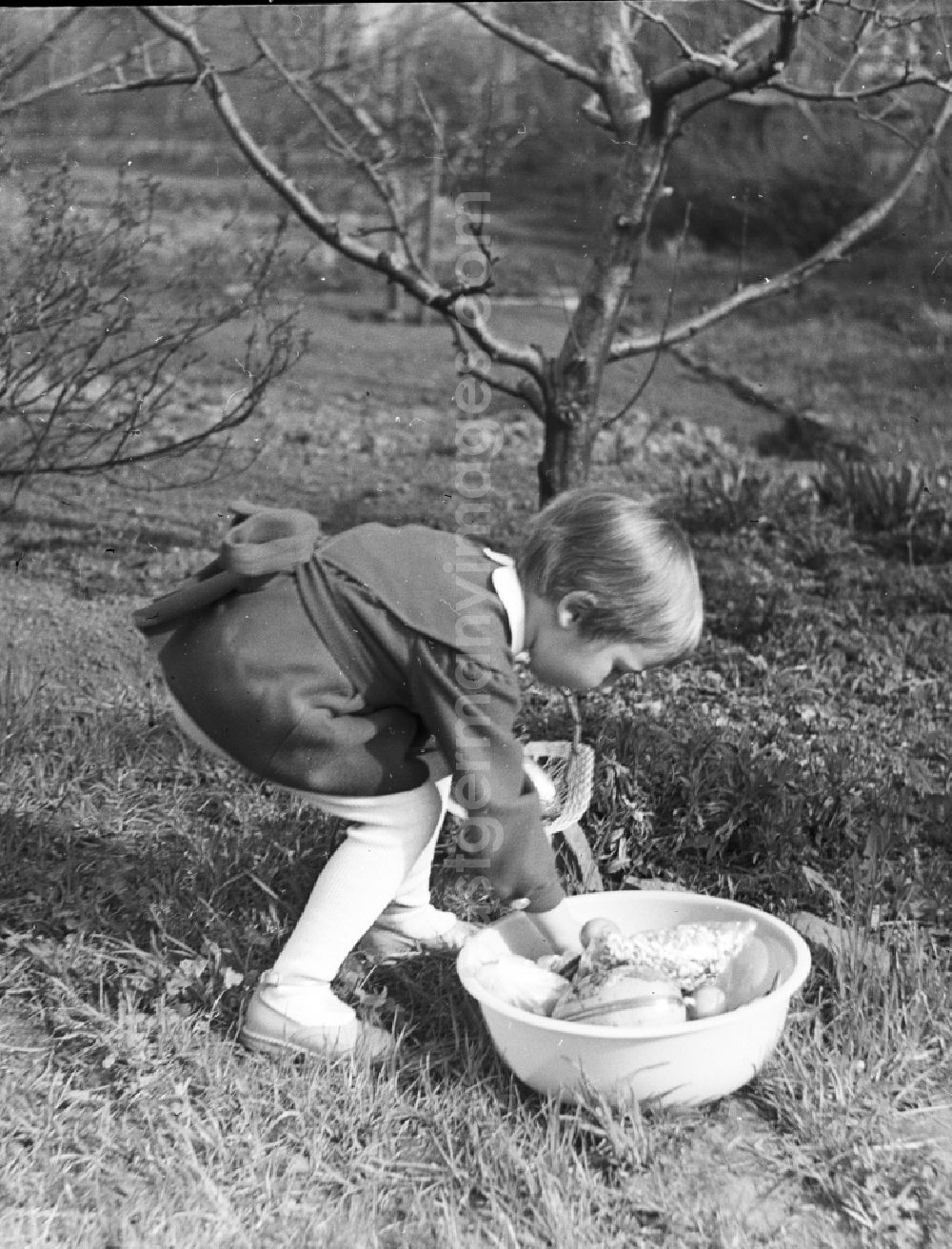 GDR picture archive: Zschopau - A small child in a dress with the Easter egg look in the garden in Zschopau in the federal state Saxony in the area of the former GDR, German democratic republic
