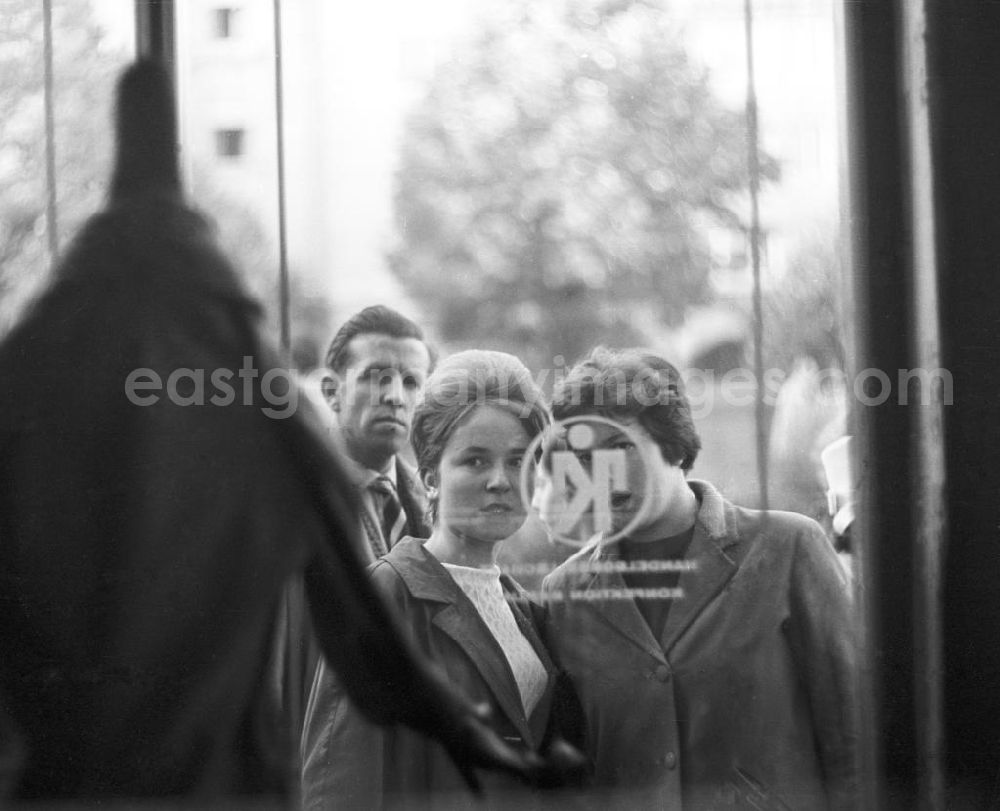 GDR photo archive: Berlin - Passanten betrachten das Schaufenster von einem Mode-Geschäft. In der Auslage, eher undeutlich, ein Kleidungsstück. Eine Frau hat eine typische 196