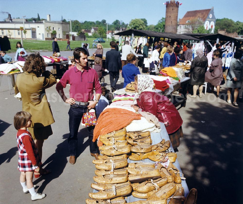 GDR photo archive: Gubin - Eine alte Frau verkauft Schuhe und Kleidung auf einem Markt in Gubin.