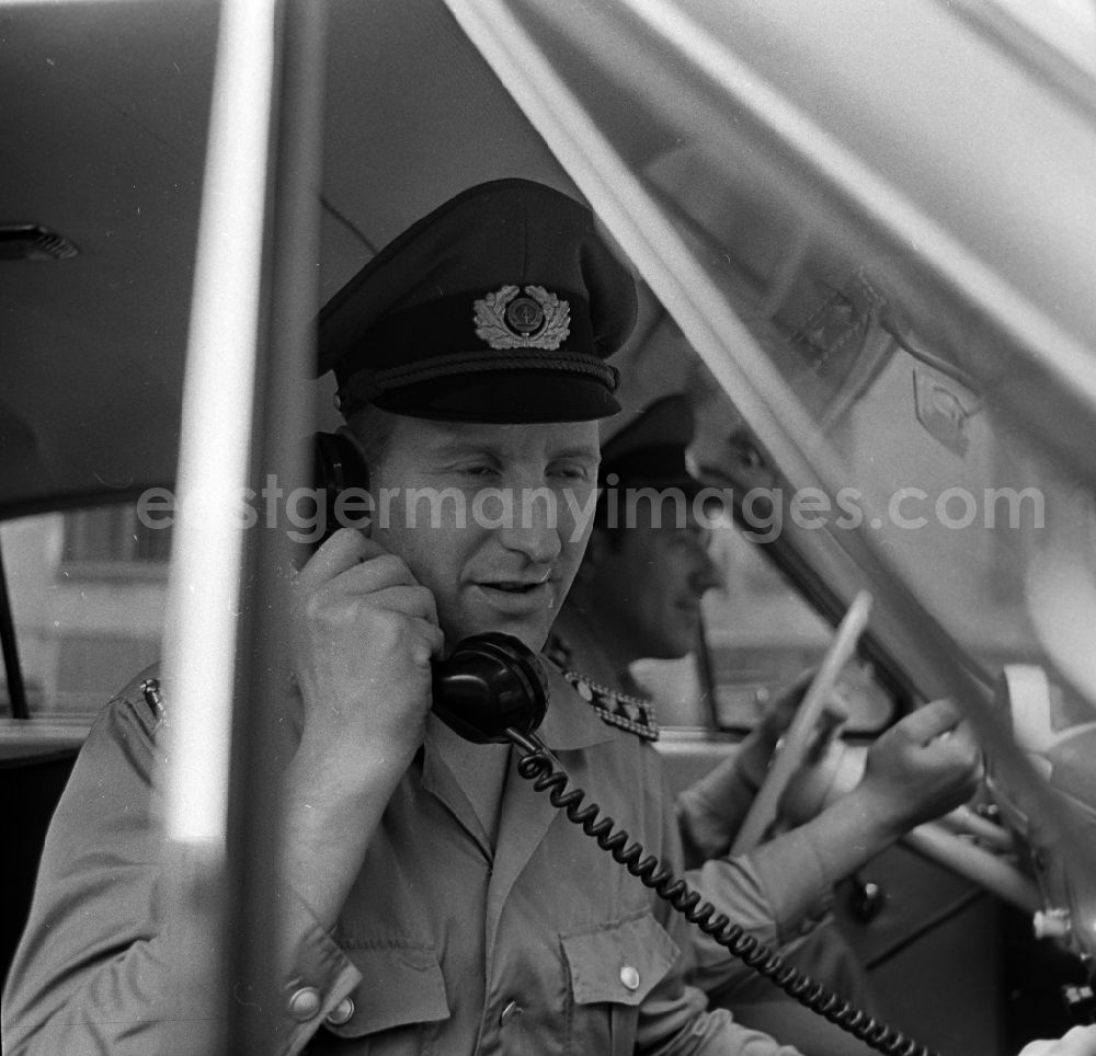 GDR picture archive: Berlin - Policeman in uniform of the VP People's Police - Master Reinhold Guenther with a telephone receiver in a radio conversation in a radio patrol car GAZ M21 Volga in the district of Pankow in Berlin East Berlin on the territory of the former GDR, German Democratic Republic