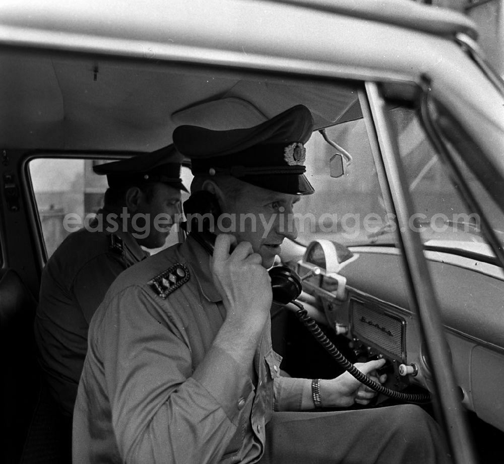 Berlin: Policeman in uniform of the VP People's Police - Master Reinhold Guenther with a telephone receiver in a radio conversation in a radio patrol car GAZ M21 Volga in the district of Pankow in Berlin East Berlin on the territory of the former GDR, German Democratic Republic