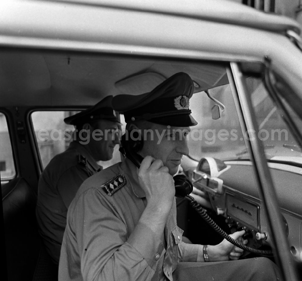 GDR image archive: Berlin - Policeman in uniform of the VP People's Police - Master Reinhold Guenther with a telephone receiver in a radio conversation in a radio patrol car GAZ M21 Volga in the district of Pankow in Berlin East Berlin on the territory of the former GDR, German Democratic Republic