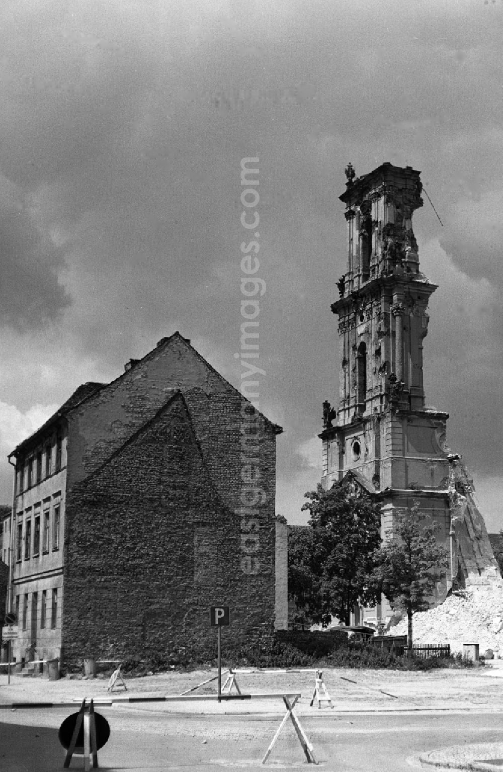 GDR picture archive: Potsdam - Abriss der Garnisonkirche. Blick von der Bauhofstraße auf die Reste vom Glockenturm. Rechts im Vordergrund eines der beiden Knobbelsdorfhäuser. Die Garnisonkirche Potsdam wurde von Philipp Gerlach zwischen 1730 und 1735 auf Befehl Friedrich Wilhelm I. errichtet. Sie galt als ein Hauptwerk des preußischen Barock. Mit einem 88,40 Meter hohen Glockenturm überragte sie die anderen Bauten der Stadt. In der offenen Turmlaterne befand sich ein holländisches Glockenspiel mit 4