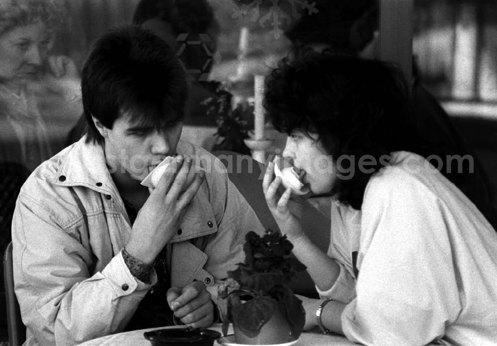 GDR image archive: Berlin - Ein Pärchen bzw. eine Frau und ein Mann sitzen zusammen in einem Eiscafé / Café beim Eis essen aus einer typischen Eiswaffel.