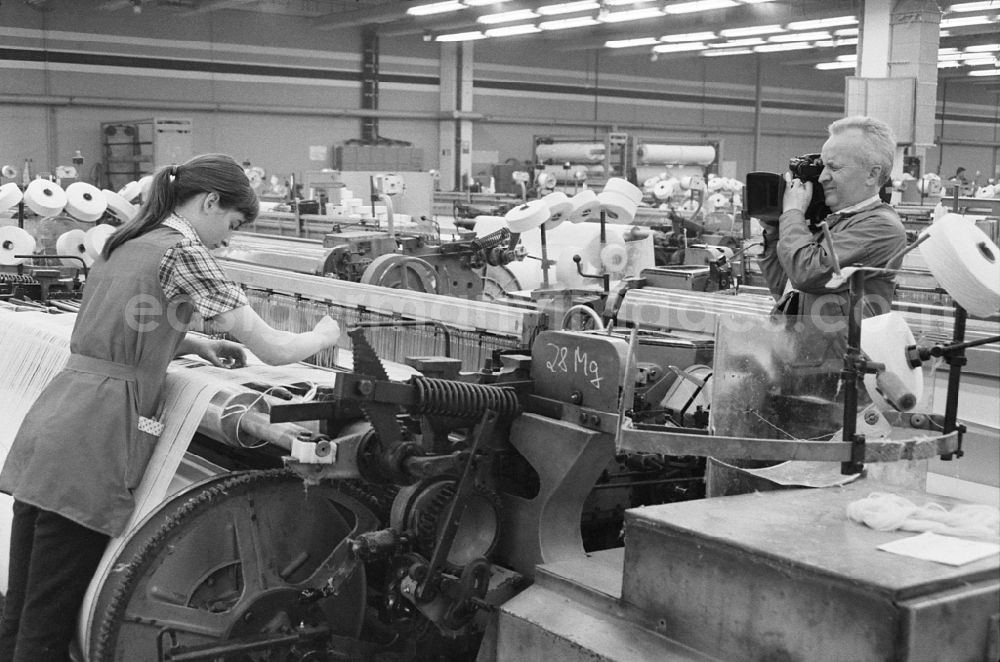 GDR image archive: Ebersbach - Women at work and factory equipment in the workshop with loom machines in the VEB Lautex spinning mill in Ebersbach in GDR. DEFA cameraman Christian Lehmann shoots a worker on the machine
