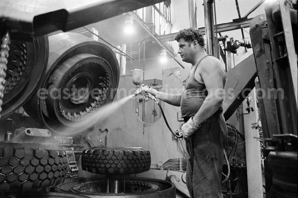 GDR photo archive: Fürstenwalde/Spree - Workers in front of a tire press, shortly after joining or vulcanizing the carcass and bladder to form a finished tire in the production plant and operating facilities of the VEB Reifenkombinat Fuerstenwalde, later Pneumant Reifen Gmbh and Goodyear, in Fuerstenwalde/Spree in the state Brandenburg on the territory of the former GDR, German Democratic Republic