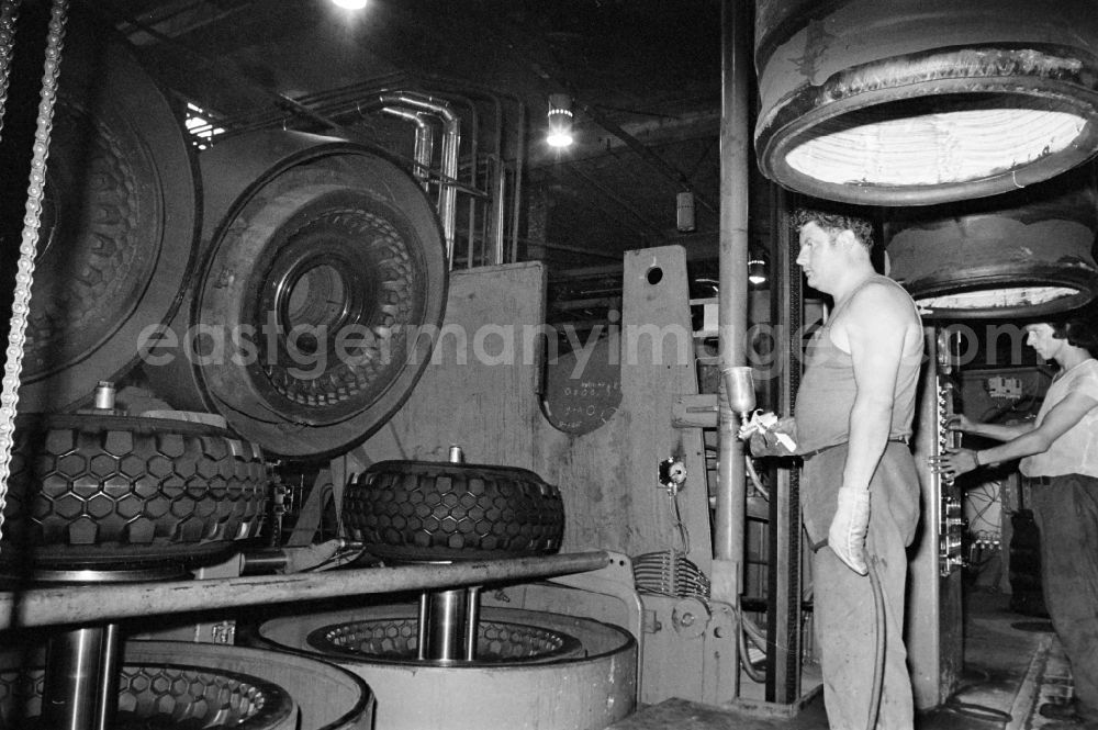 Fürstenwalde/Spree: Workers in front of a tire press, shortly after joining or vulcanizing the carcass and bladder to form a finished tire in the production plant and operating facilities of the VEB Reifenkombinat Fuerstenwalde, later Pneumant Reifen Gmbh and Goodyear, in Fuerstenwalde/Spree in the state Brandenburg on the territory of the former GDR, German Democratic Republic