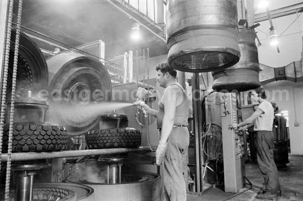 GDR image archive: Fürstenwalde/Spree - Worker in front of a tire press, shortly before joining or vulcanizing carcass and bladder to form a finished tire in the production plant and operating facilities of the VEB Reifenkombinat Fuerstenwalde, later Pneumant Reifen Gmbh and Goodyear, in Fuerstenwalde/Spree in the state Brandenburg on the territory of the former GDR, German Democratic Republic