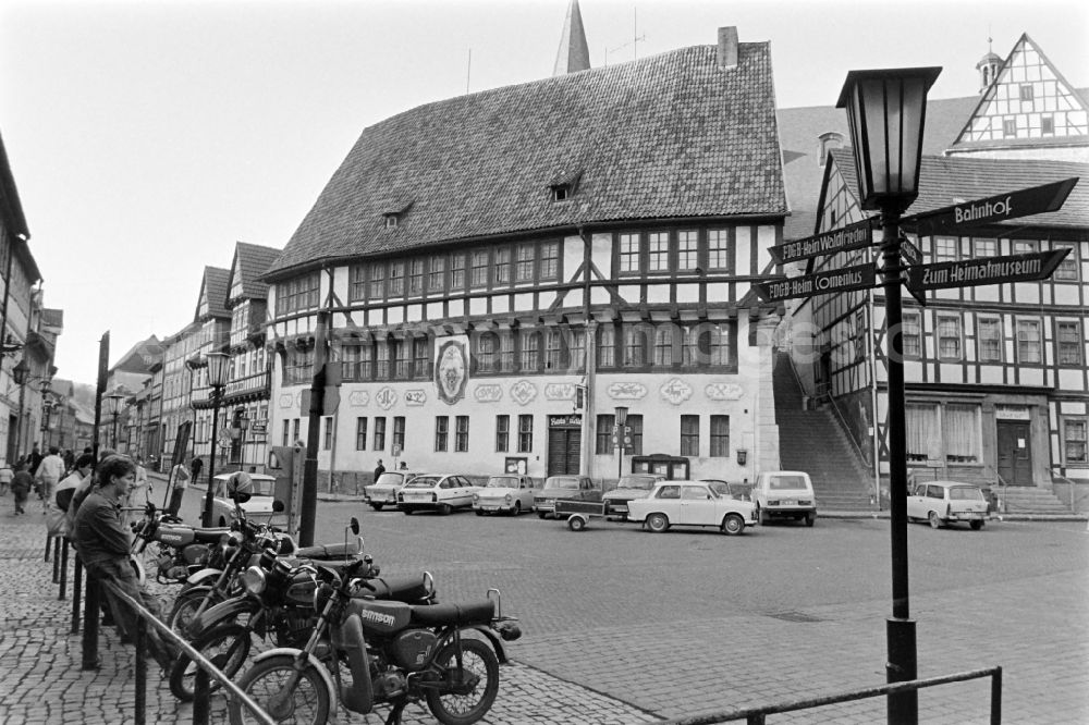 Südharz: The town hall of Stolberg (Harz) in the southern Harz region in the federal state of Saxony-Anhalt on the territory of the former GDR, German Democratic Republic. Model Simson motorbikes and cars are parked on the street. A signpost shows the direction to the FDGB recreation home Comenius and Waldfrieden 