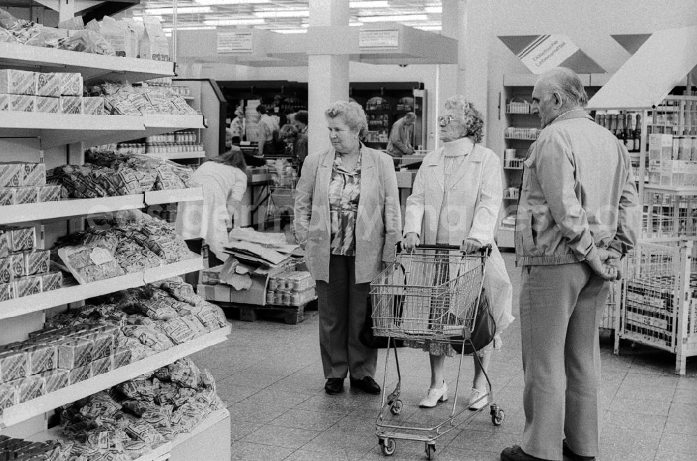 GDR photo archive: Berlin - A woman shopping in a department store in Berlin, the former capital of the GDR, the German Democratic Republic. The shelves are filled partly with East products as well with Western products