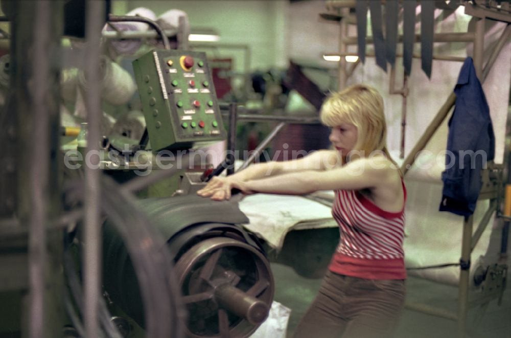 GDR picture archive: Neubrandenburg - Young woman as a worker at work and factory equipment for tire production in the VEB tire factory on Ihlenfelder Strasse in Neubrandenburg in the state of Mecklenburg-Western Pomerania on the territory of the former GDR, German democratic republic