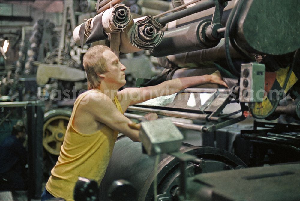 GDR picture archive: Neubrandenburg - Young woman as a worker at work and factory equipment for tire production in the VEB tire factory on Ihlenfelder Strasse in Neubrandenburg, of Mecklenburg-Western Pomerania on the territory of the former GDR, German democratic republic