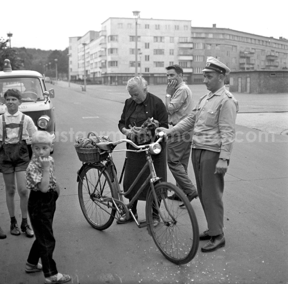 GDR photo archive: Rostock - Eine alte Frau ist mit ihrem Fahrrad auf einer Straße in Rostock gestürz, ein Passant und ein Verkehrspolizist helfen ihr wieder auf die Beine. Der Einkaufsbeutel am Lenkrad hatte sich in den Speichen verfangen.