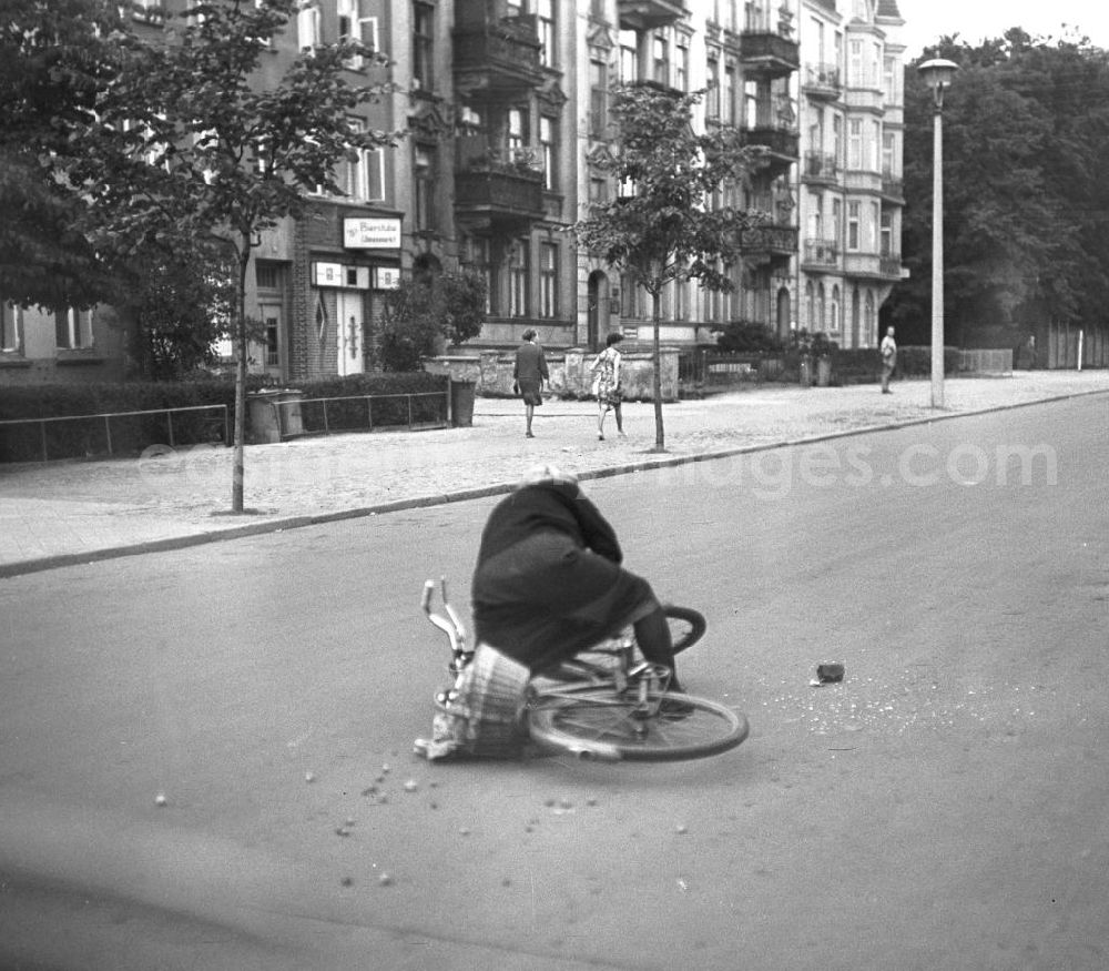 GDR image archive: Rostock - Eine alte Frau stürzt mit ihrem Fahrrad auf einer Straße in Rostock. Der Einkaufsbeutel am Lenkrad hatte sich in den Speichen verfangen.