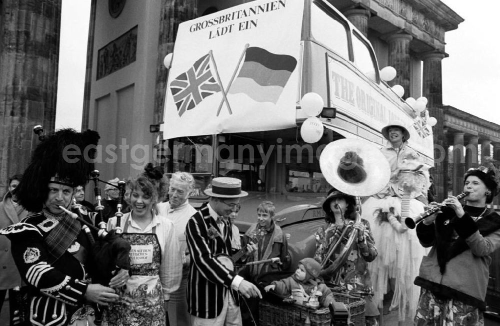 GDR photo archive: Berlin-Mitte - Roter Doppeldecker Bus Routemaster und Akteure / Musiker anläßlich zum Besuch der Königin Elisabeth II. (Queen Elisabeth II.) vor dem Brandenburger Tor. Plakat an Bus mit der Aufschrift Grossbritannien lädt ein sowie Flagge Großbritannien und Deutschland.