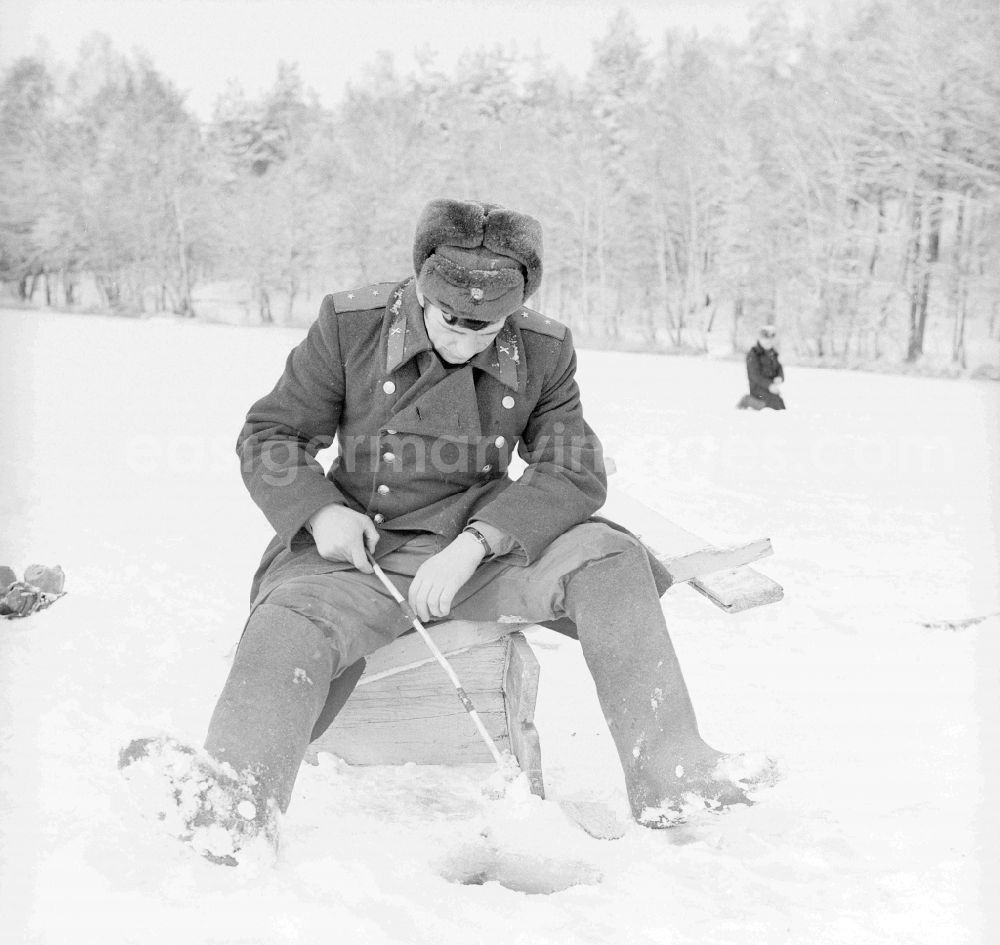 GDR image archive: Wittstock/Dosse - Russian soldier in winter uniform with the ice fish on the small Baalsee in Wittstock / Dosse in the federal state Brandenburg in the area of the former GDR, German democratic republic