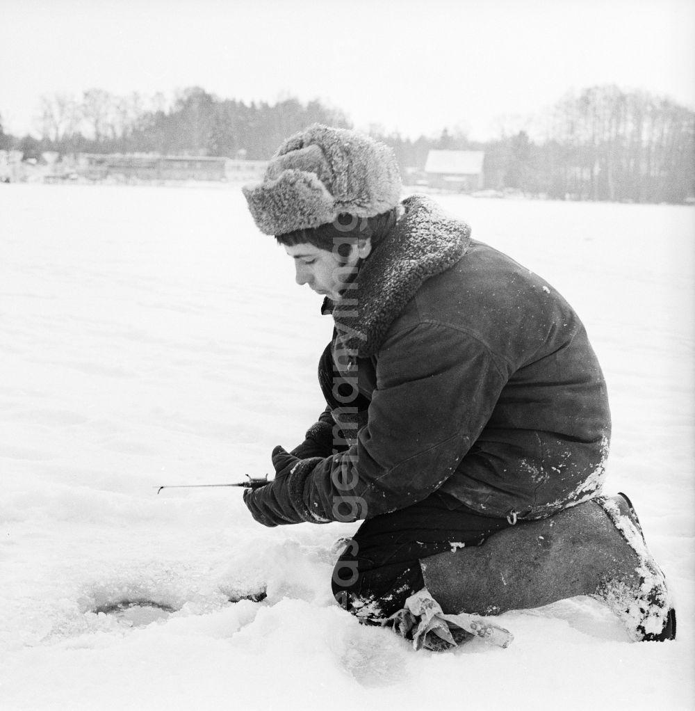 GDR photo archive: Wittstock/Dosse - Russian soldier in winter uniform with the ice fish on the small Baalsee in Wittstock / Dosse in the federal state Brandenburg in the area of the former GDR, German democratic republic