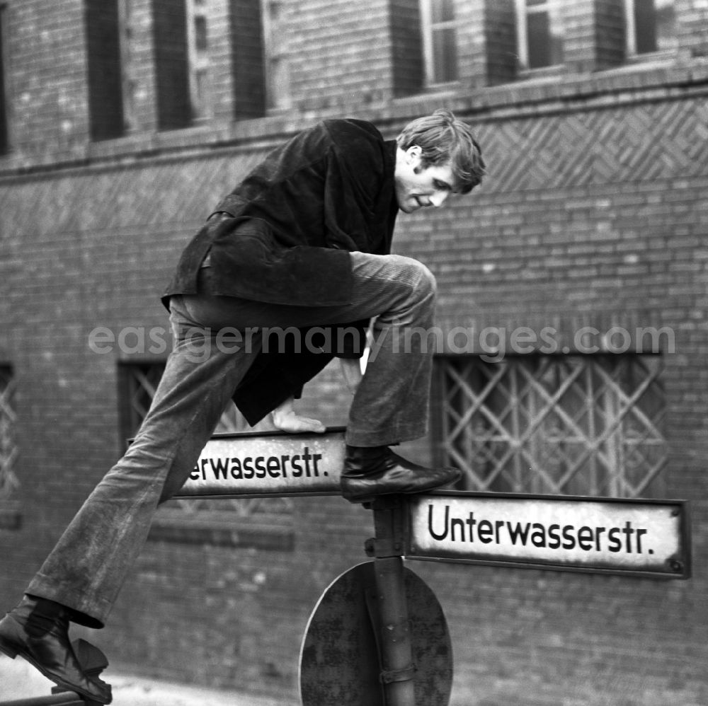 GDR image archive: Berlin - Actor Reiner Schoene climbs a street sign on the Unterwasserstrasse in Berlin-Mitte in the area of the former GDR, German Democratic Republic
