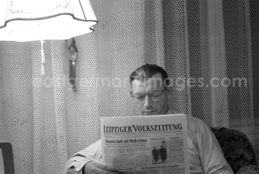 Leipzig: Ein Mann sitzt in seinem Wohnzimmer und liest in der Leipziger Volkszeitung die neuesten Nachrichten - Schlagzeilen wie Freundschaft mit Volkschina und Der Sozialismus ist unsere Perspektive prägen die Titelseite.