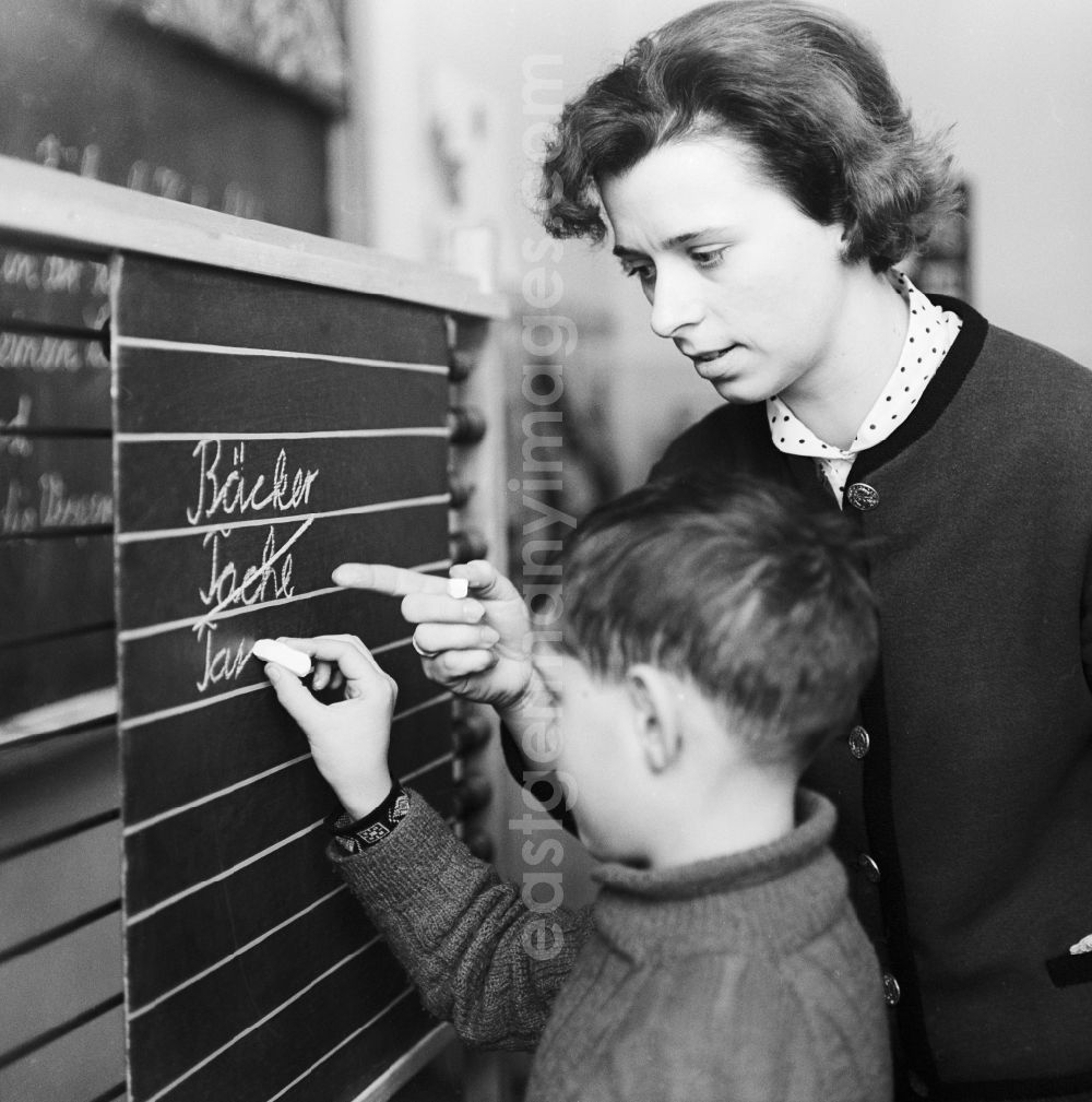 GDR photo archive: Berlin - Students of the lower level with his teacher at blackboard teaching of German in Berlin. The German-classes were divided into four separate subjects: reading, writing, spelling and grammar, as well as oral and written expression