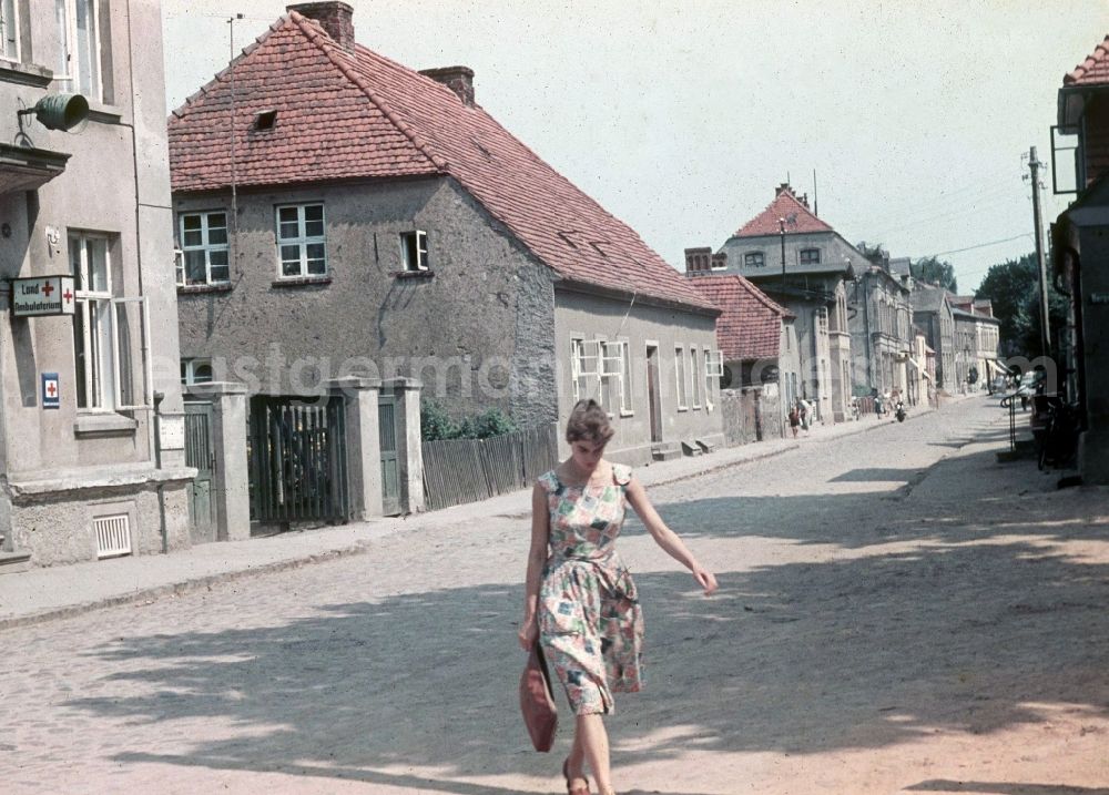 Neustrelitz: A young woman crosses Schlossstrasse with the Landambulatorium in Neustrelitz in the federal state Mecklenburg-West Pomerania in the area of the former GDR, German democratic republic