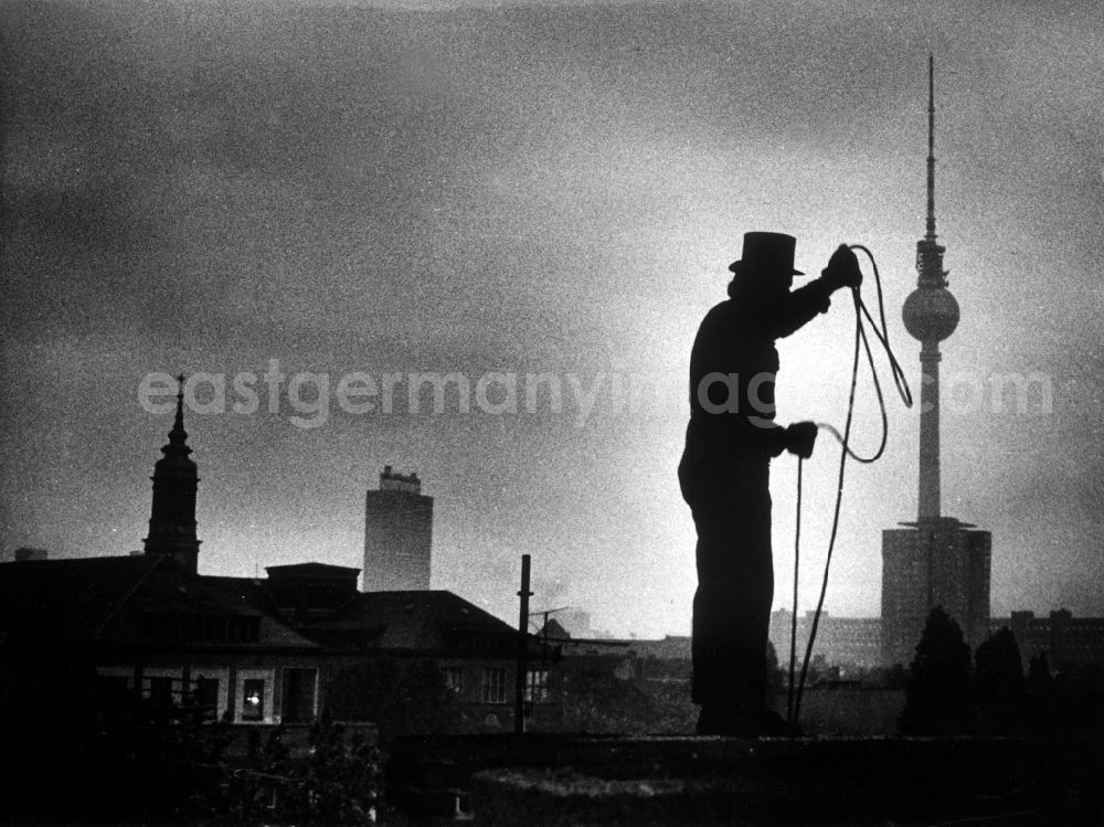 GDR picture archive: Berlin - Chimney sweep in typical working clothes with equipment of his craft in Berlin Eastberlin on the territory of the former GDR, German Democratic Republic. In the background, the Berlin television tower