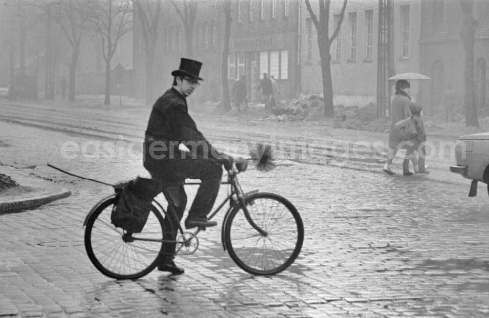 GDR image archive: Potsdam - Chimney sweep in typical working clothes with equipment of his craft on a bike in the district Babelsberg in Potsdam, Brandenburg on the territory of the former GDR, German Democratic Republic