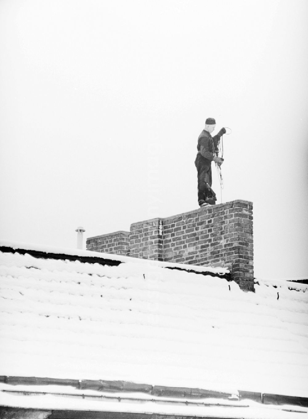 Berlin: A chimney sweep on snow-covered roofs round the chimneys in Berlin, the former capital of the GDR, German Democratic Republic