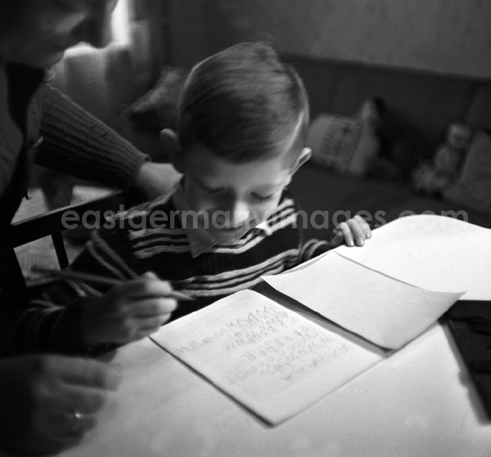 Leipzig: Ein Junge sitzt an einem Tisch im Wohnzimmer seines zu Hauses in Leipzig und lernt mit Hilfe seiner Mutti / Mama erstes Schreiben.